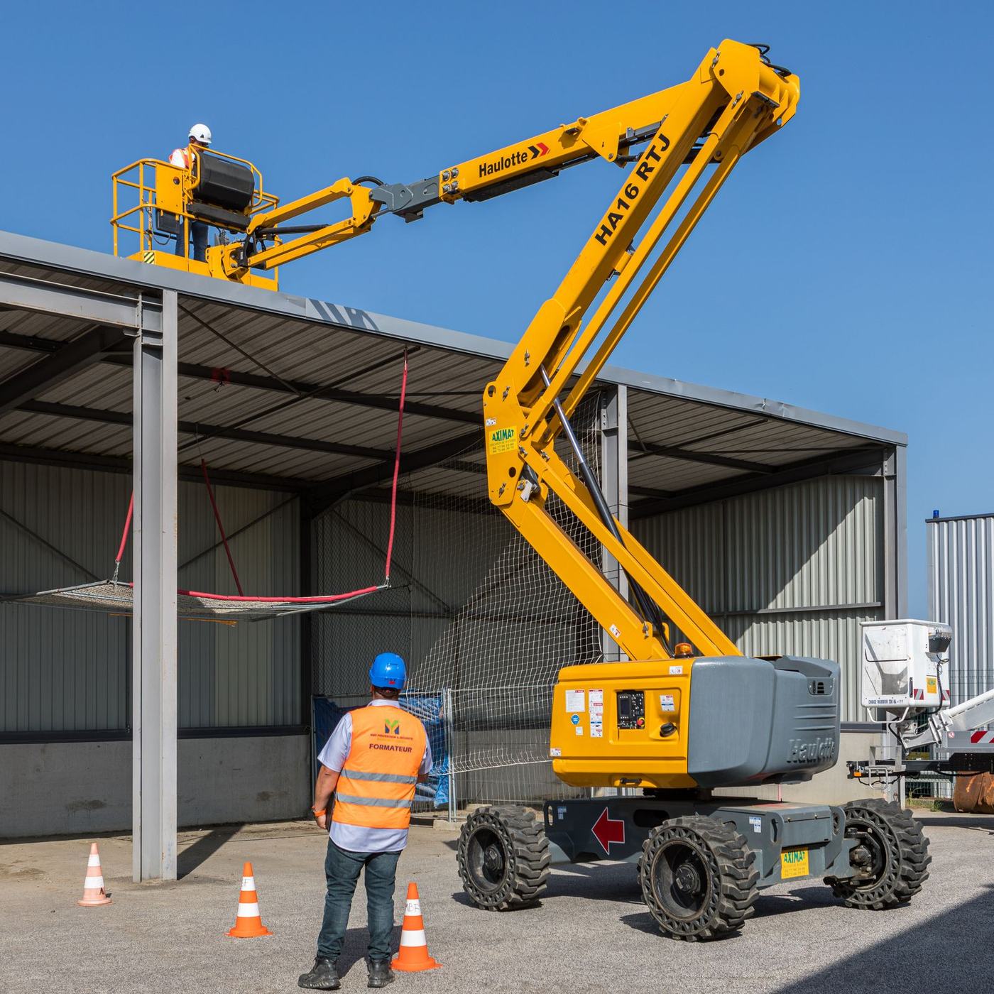 Formation CACES® R486 catégorie B : nacelle articulée en évolution près d'une structure, zone balisée