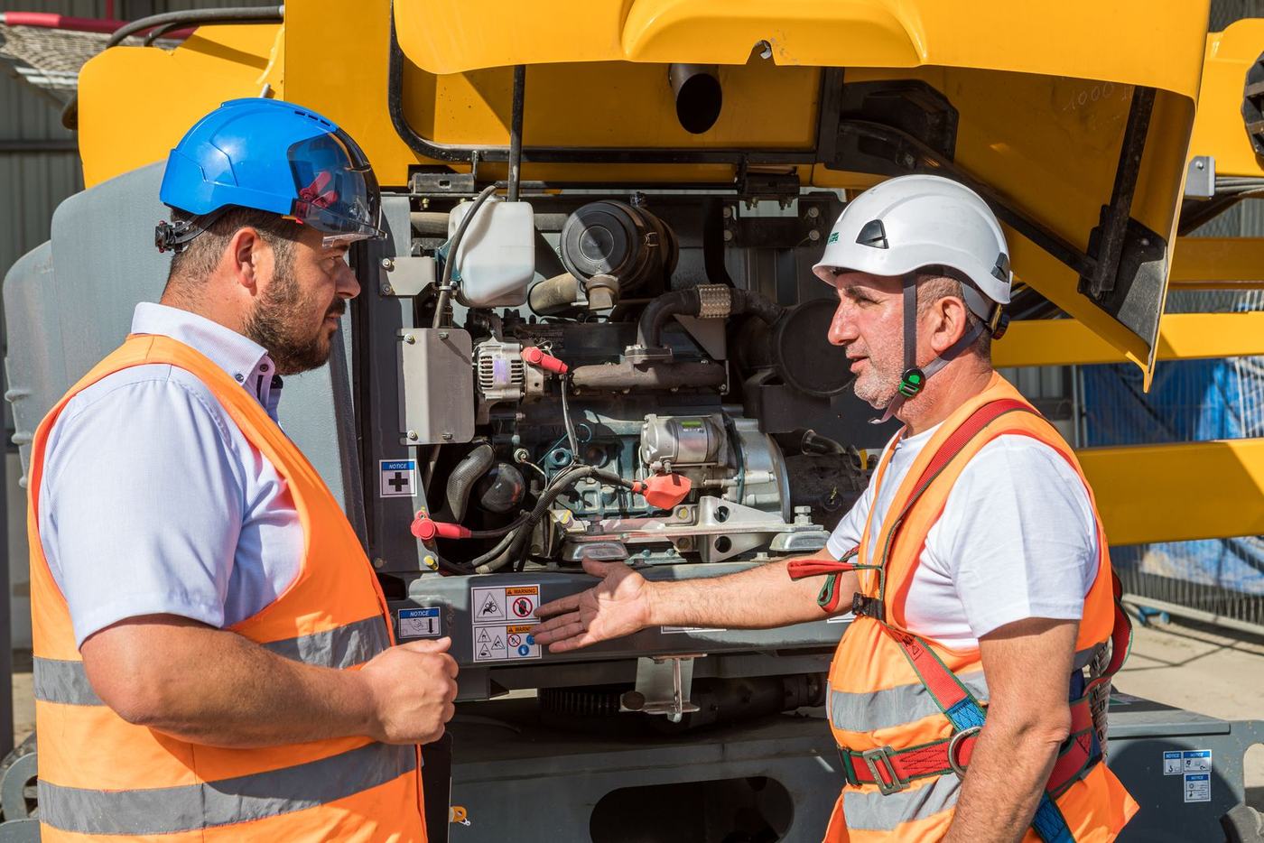 Formateur et stagiaire vérifiant le compartiment moteur d'une nacelle avant utilisation