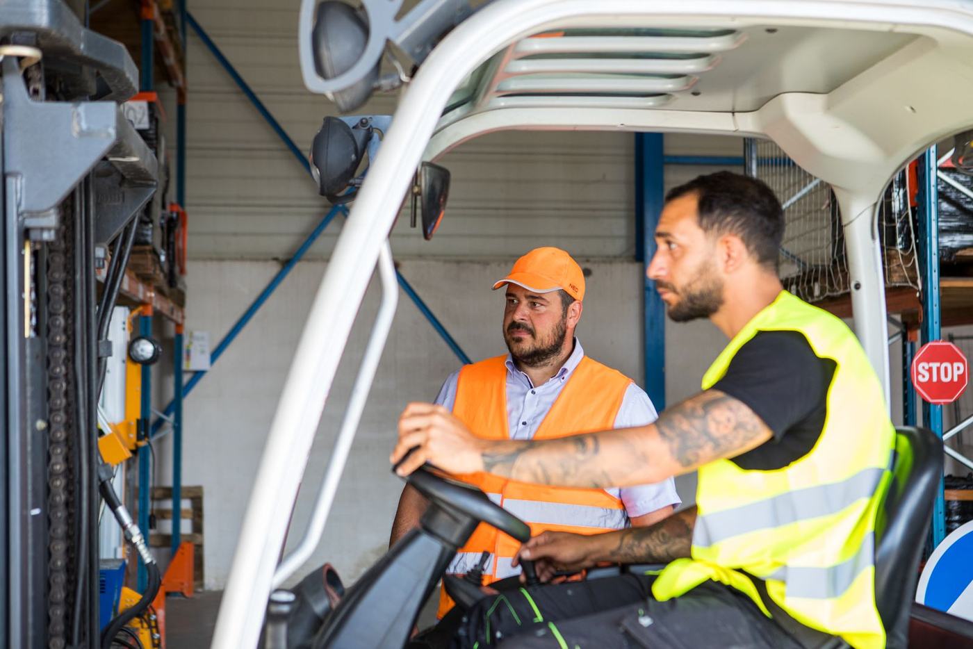 Formateur MBF expliquant les commandes d'un chariot élévateur à un stagiaire cariste