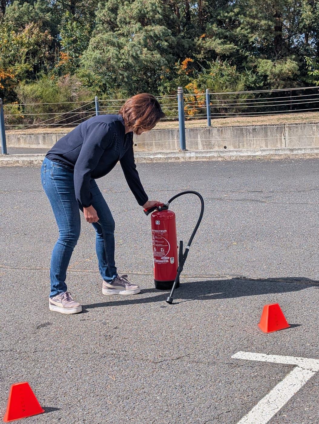 Stagiaire préparant et dégoupillant un extincteur avant l'exercice